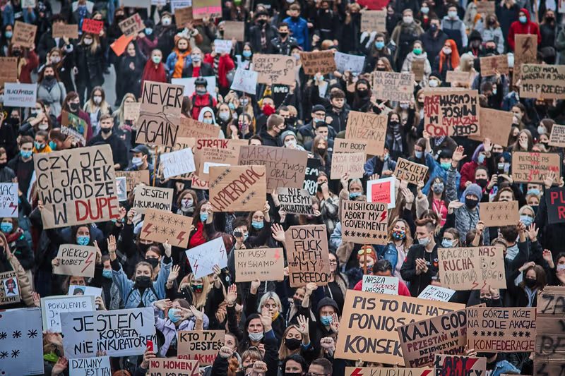 Protesters holding handmade cardboard placards at a Strajk Kobiet demonstration